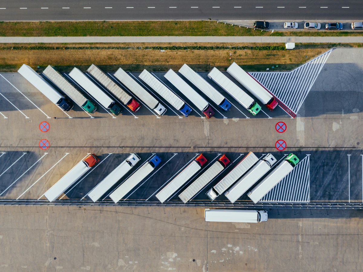 Fleet of delivery trucks parked side by side at a logistics depot