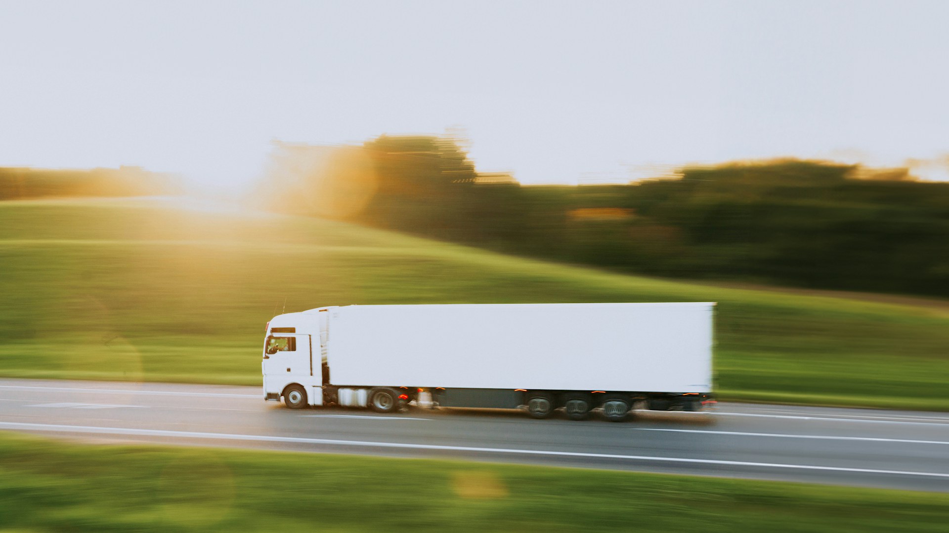 White semi-truck driving along a rural highway