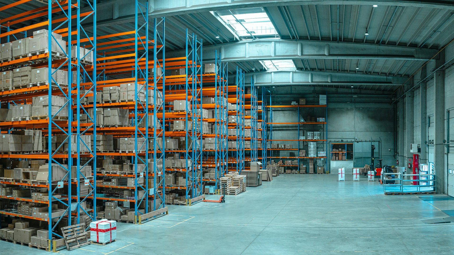 Tall blue shelving units filled with boxes in a large distribution warehouse